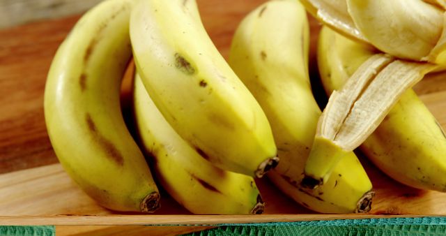 A bunch of ripe bananas rests on a wooden cutting board, with copy space. Bananas are a nutritious fruit, high in potassium and fiber, and popular for snacks or as an ingredient in various dishes.