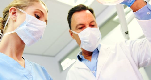 Healthcare Professionals Wearing Masks Treating Patient in Modern Clinic - Download Free Stock Images Pikwizard.com