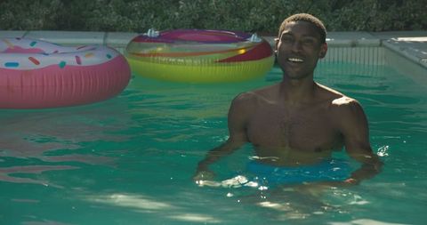 Smiling Man Enjoying Summer in Swimming Pool with Inflatable Supplies