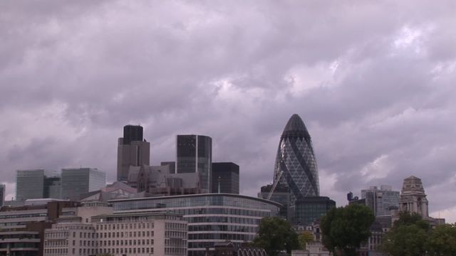 The video captures a London skyline with notable skyscrapers such as the Gherkin, under a cloudy, overcast sky in a time lapse sequence. This video can be used for illustrating urban planning, architectural projects, weather-related content, or promoting tourism in London.