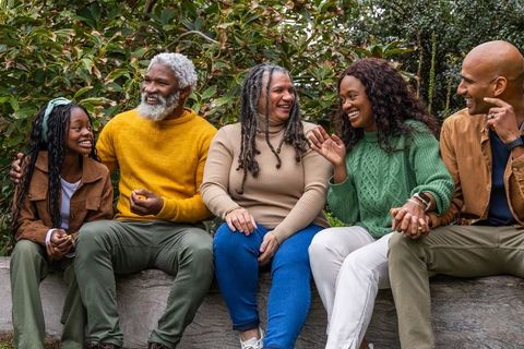 African american multigenerational family laughing and holding hands on park bench