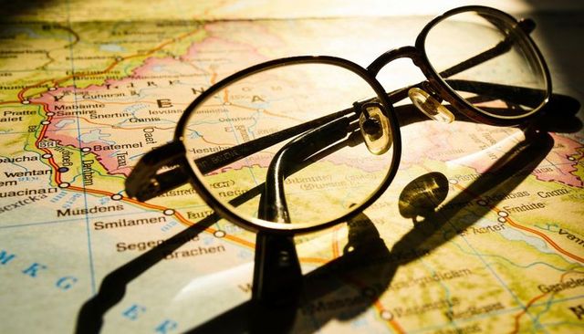 Vintage round eyeglasses casting long shadows over roadmap for travel planning concept