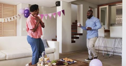 African american couple exchanging surprise jar during intimate birthday celebration