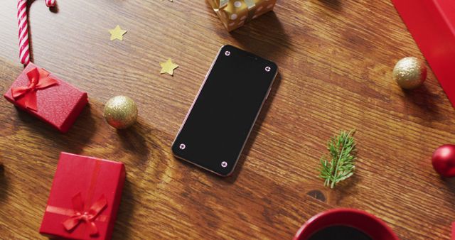 Image of christmas decorations and presents with smartphone on wooden table. christmas, communication, tradition and celebration concept.