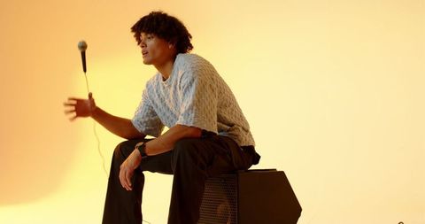 Musician relaxing in studio with microphone and speaker setup