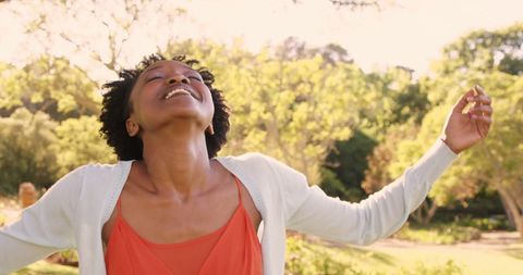 Joyful Woman Embracing Sunlight with Open Arms Outdoors