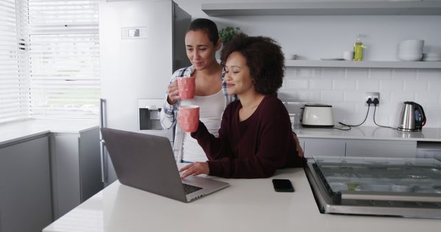 Two Women Drinking Coffee and Using Laptop in Modern Kitchen - Download Free Stock Images Pikwizard.com