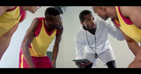 Basketball Coach Strategizing with Team Using Tablet