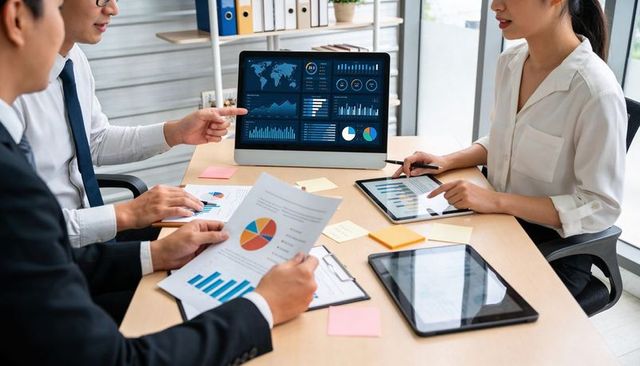 Business team analyzing digital dashboards and charts in collaborative meeting room