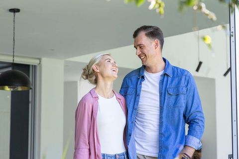 Young couple standing in bright modern home doorway smiling and sharing moment
