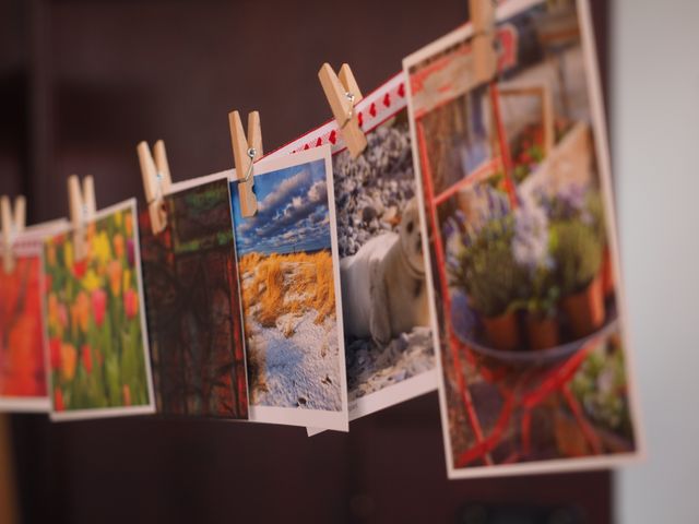 Various colorful photos are hanging on a clothesline indoors, secured by wooden clothespins. Ideal for themes related to decoration, DIY home decor, crafts, photography, and creative ideas for displaying pictures.