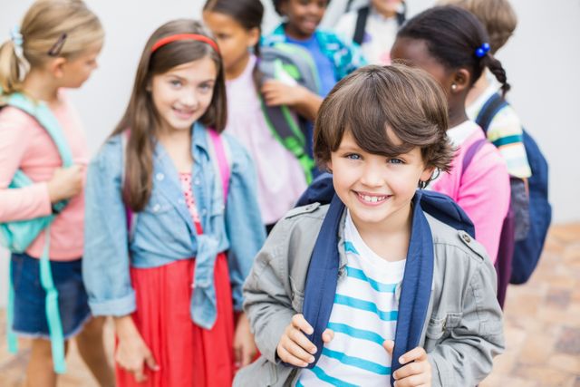 Group of cheerful school children wearing backpacks, standing outdoors. Ideal for educational materials, back-to-school promotions, and advertisements focusing on childhood education and friendship.