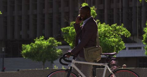 Professional Man on Smartphone Walking with Bicycle in City - Download Free Stock Images Pikwizard.com