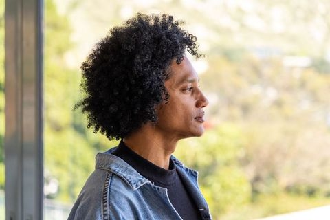 Contemplative african american man gazing out window wearing denim jacket and dark sweater