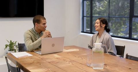 Two professionals collaborating in modern office meeting room