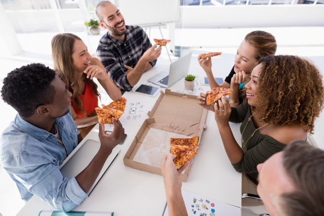Group of executives interacting while having pizza in conference room