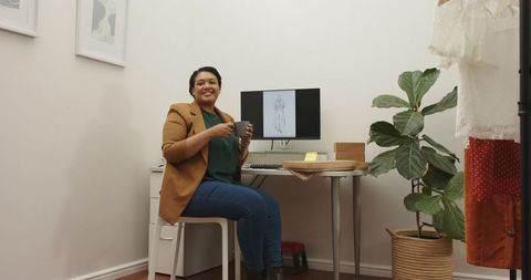 African American Fashion Designer Smiling and Holding Mug in Home Studio Workspace