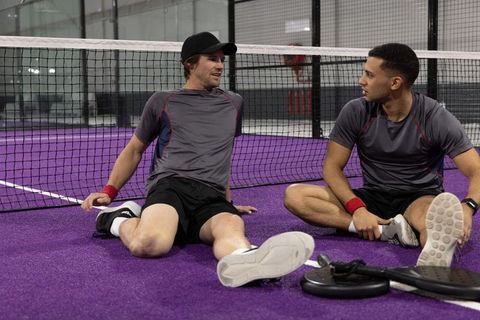 Two male players resting on purple indoor pickleball court after practice