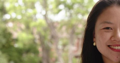 Asian woman smiling at camera showing gold stud earring long hair outdoor portrait garden