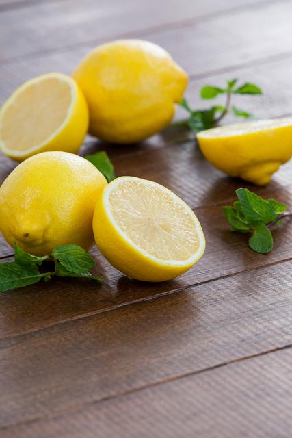 Bright yellow lemons and fresh green mint leaves on a wooden table, perfect for illustrating healthy eating, cooking ingredients, or refreshing beverages. Ideal for food blogs, recipe websites, or health and wellness content.