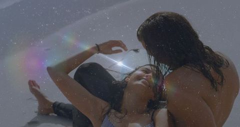 Sunlit beach romance: couple lounging on pale sand with soft lens flare and glow