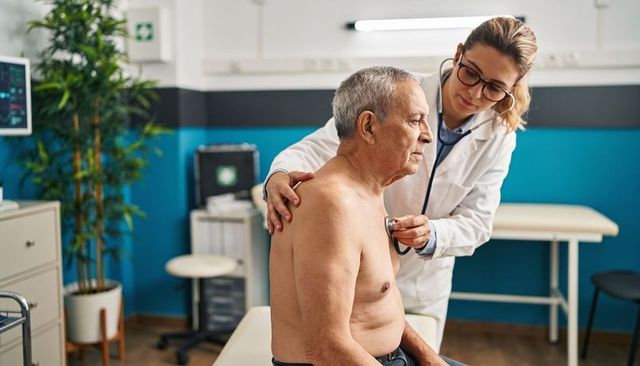 Female doctor listening to senior male chest with stethoscope during medical checkup