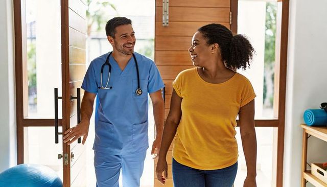 Smiling clinician welcoming patient into bright wellness clinic with wooden door