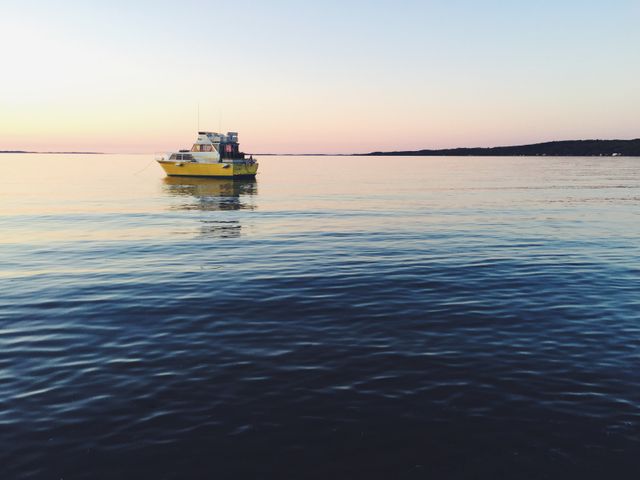 Beautiful tranquil sunset scene on the calm sea with a yellow boat floating in isolation. Ideal for travel brochures, nature calendars, nautical themes, and inspirational backgrounds promoting relaxation and tranquility.