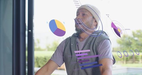 Senior asian man viewing ar fitness charts while holding stationary bike handlebars