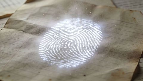 Glowing biometric fingerprint projecting onto aged lined paper with dust halo and specks