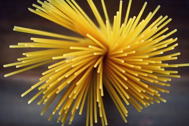 This image of uncooked spaghetti pasta seen from an overhead view can be used for culinary blogs, cookbook illustrations, food packaging designs, and restaurant menus. Great for emphasizing quality ingredients and visually engaging content in food-related projects.
