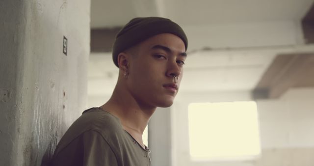 Young Urban Man with Beanie Posing Against Concrete Wall in Industrial Space - Download Free Stock Images Pikwizard.com