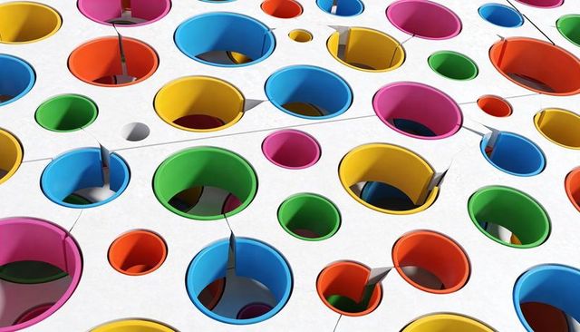 Multicolor perforated panel showing circular openings with colored rims and tabs