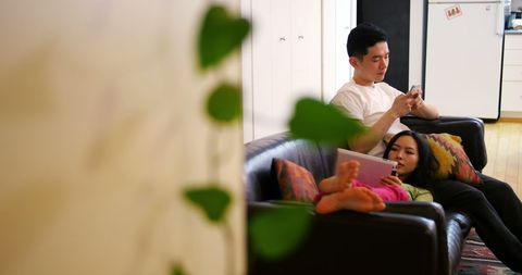 Couple Relaxing Using Devices on Sofa in Cozy Living Room