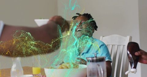 Multigenerational family laughing at breakfast table, pouring syrup over pastries, joy