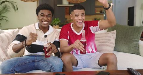 Excited Friends Cheering on Sofa in Living Room