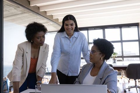 Diverse Female Team Collaborates Around Laptop in Modern Office