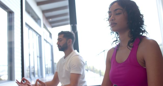 Young couple meditating for stress relief in a modern home, focusing on mindfulness and relaxation. Ideal for use in wellness blogs, mental health resources, lifestyle articles, and yoga promotion.