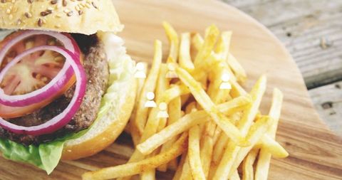Gourmet hamburger and seasoned fries on rustic wood