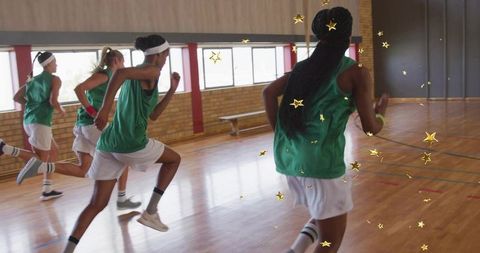 Teammates Training in Green Jerseys on Indoor Basketball Court