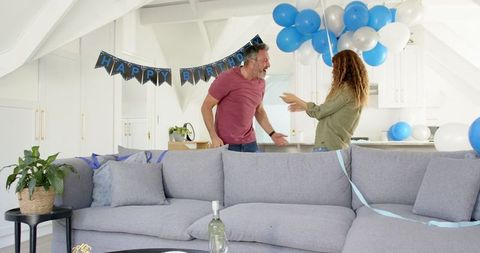 Mature Couple Celebrating Birthday in Festive Living Room with Balloons