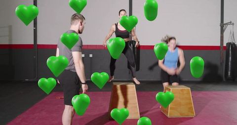 Instructor guiding group plyometric box jumps with green heart overlays in gym studio