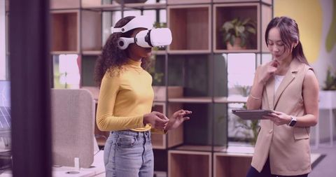 Coworkers Utilizing VR Headset in Modern Office Environment