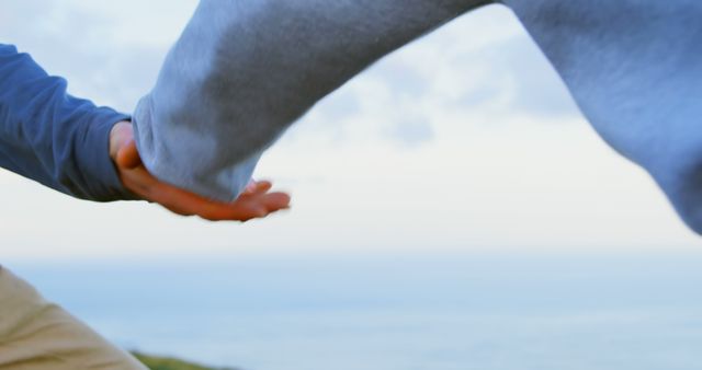 Two people are holding hands against a serene sky, with copy space - Download Free Stock Photos Pikwizard.com