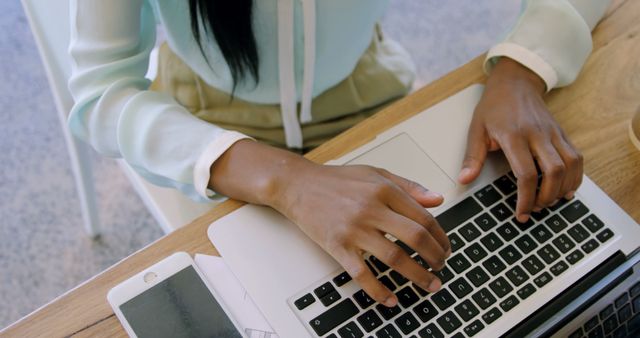 Professional working on laptop at wooden desk with smartphone close-up - Download Free Stock Images Pikwizard.com