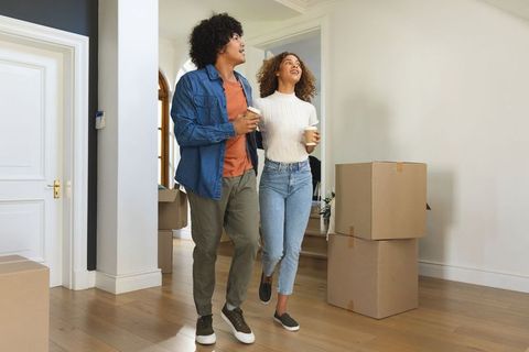 Young african american couple touring new home holding coffee amid moving boxes and joy