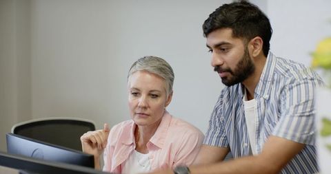 Diverse coworkers collaborating on work project with dual monitors