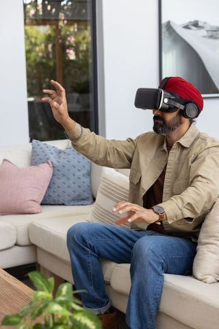 Man with turban enjoying virtual reality in modern living room