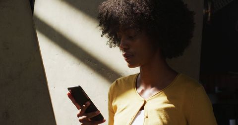 Young Woman in Yellow Cardigan Using Smartphone by Window - Download Free Stock Images Pikwizard.com
