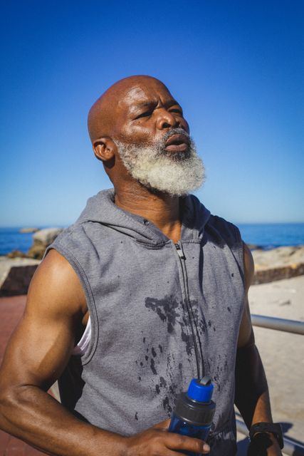 African american senior man holding water bottle taking a break from running. retirement sports and active senior lifestyle.